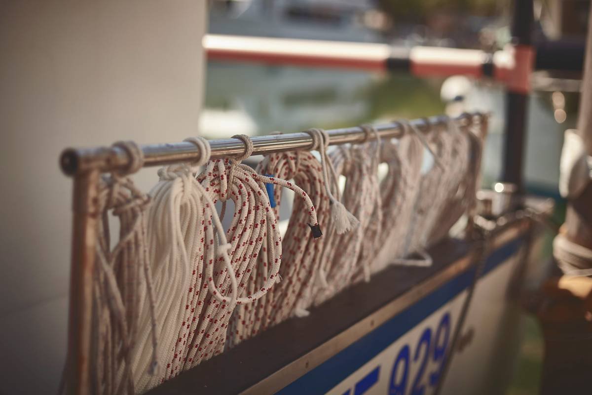 a close up of a rope fence with a boat in the background