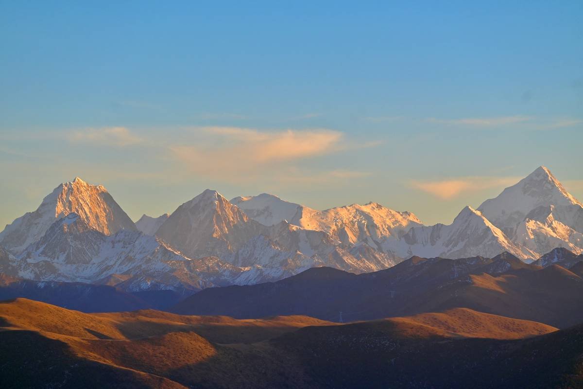 Snow-capped mountains bathed in golden sunset light.